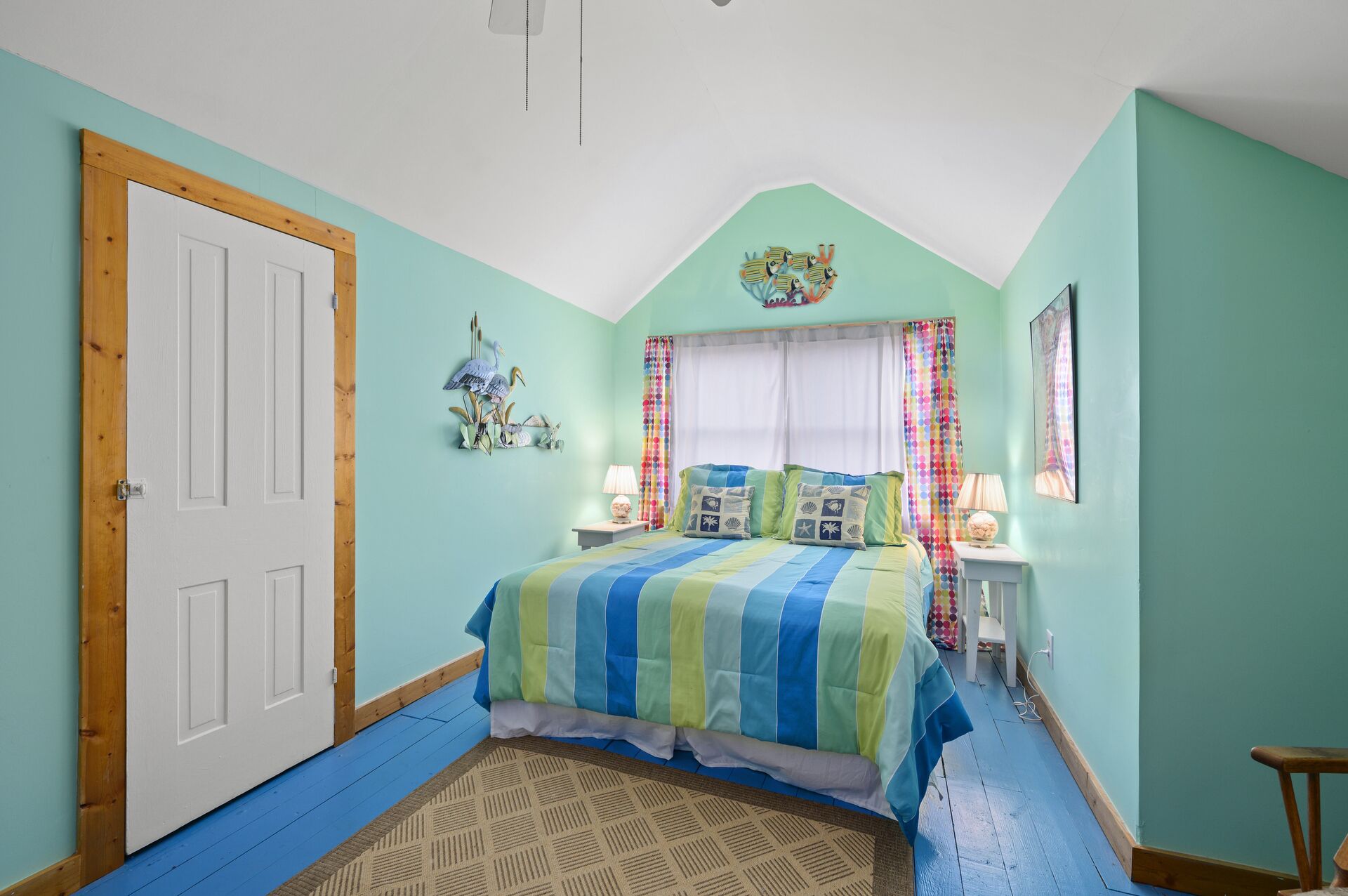 Un dormitorio con cama, una puerta, una ventana con cortinas y un adorno en la pared.