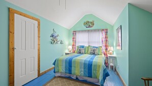 Una camera da letto con un letto, una porta, una finestra con tende e una decorazione a parete.
