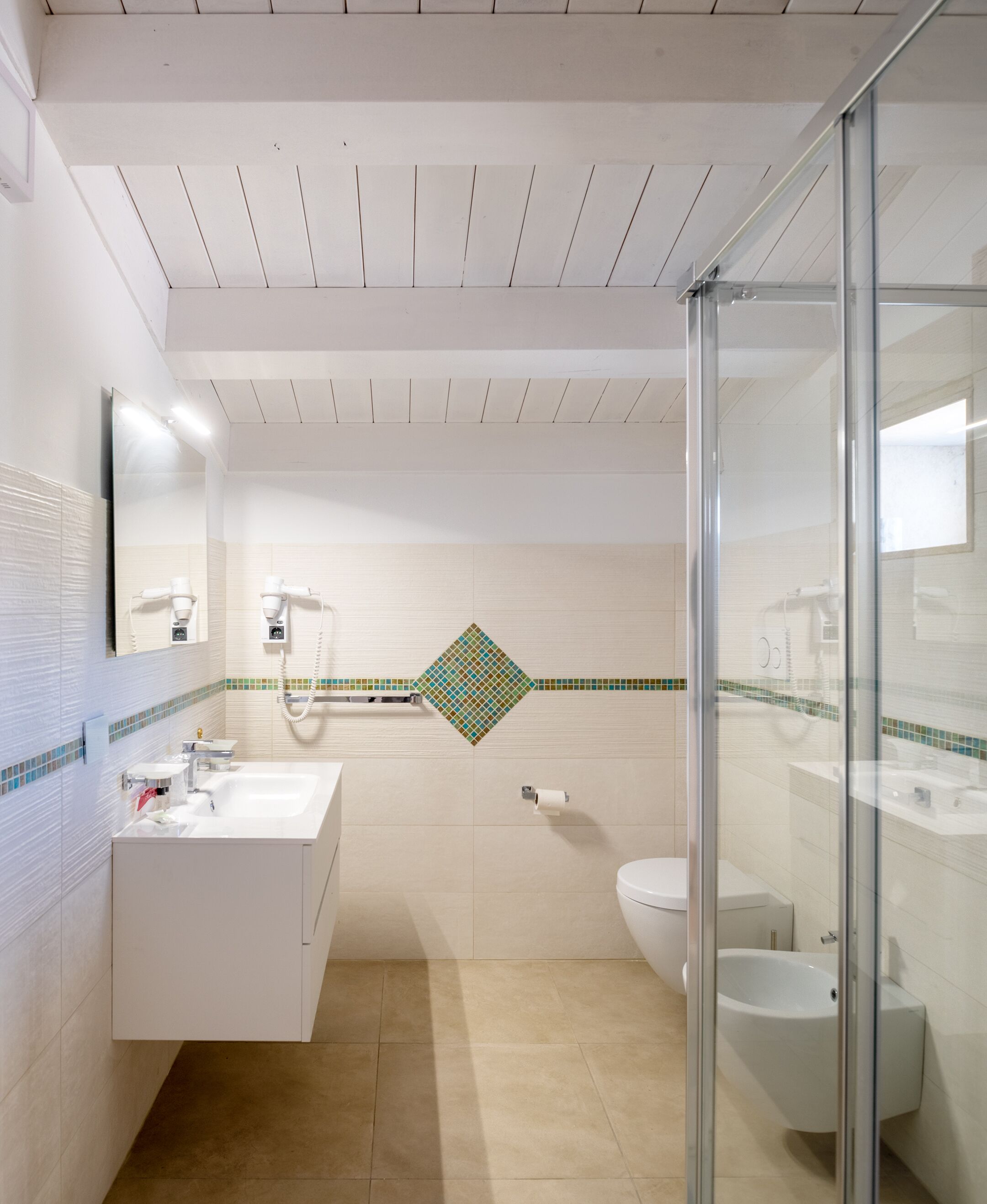 A modern bathroom with a white vanity, a glass shower enclosure, and a toilet.