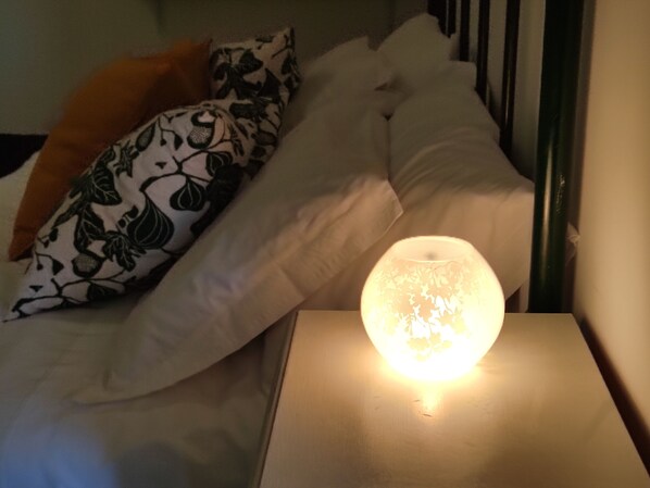 A bed with white and patterned pillows, a bedside lamp, and a wooden nightstand.