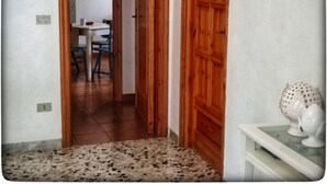 Un pasillo con piso de baldosas, puertas de madera y un comedor con mesa y sillas.