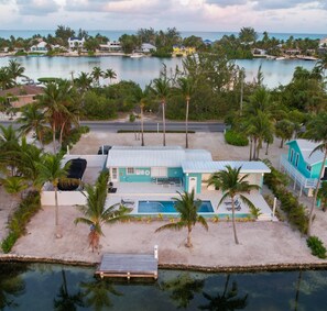 A beachfront property with a pool, palm trees, and a view of the ocean. - Kai Baby Waterfront Cottage Private Pool Cabana Kayaks Paddleboards & Bikes! (Rum Point)