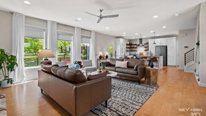 Un vaste espace de vie comprenant un canapé en cuir marron, une table basse et un tapis à motifs.