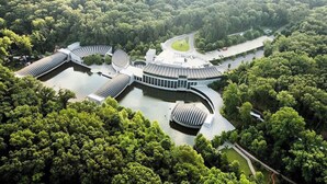 Vue aérienne d’un complexe immobilier moderne doté d’une cour intérieure, entouré d’une végétation luxuriante.