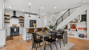 Une cuisine moderne avec des meubles blancs, un îlot central et un coin repas doté de chaises noires.