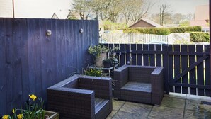 A patio with wicker furniture and potted plants. - 2 bedroom accommodation in Bamburgh (Bamburgh)