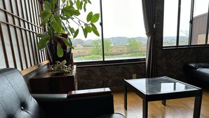 Ein modernes Wohnzimmer mit einem Ledersofa, einem Glastisch und einer Topfpflanze.