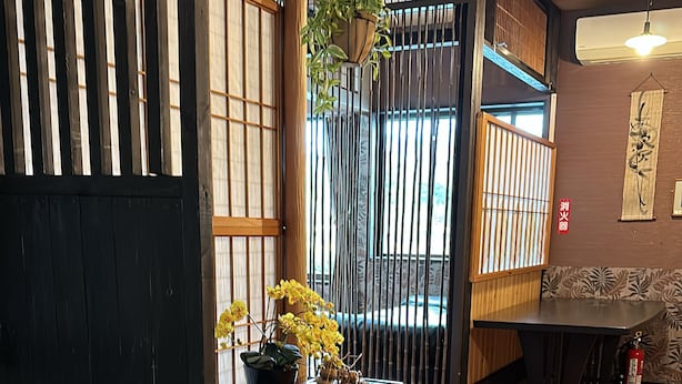 Ein traditioneller japanischer Raum mit Tatami-Böden, einem niedrigen Holztisch und einer Schiebetür.