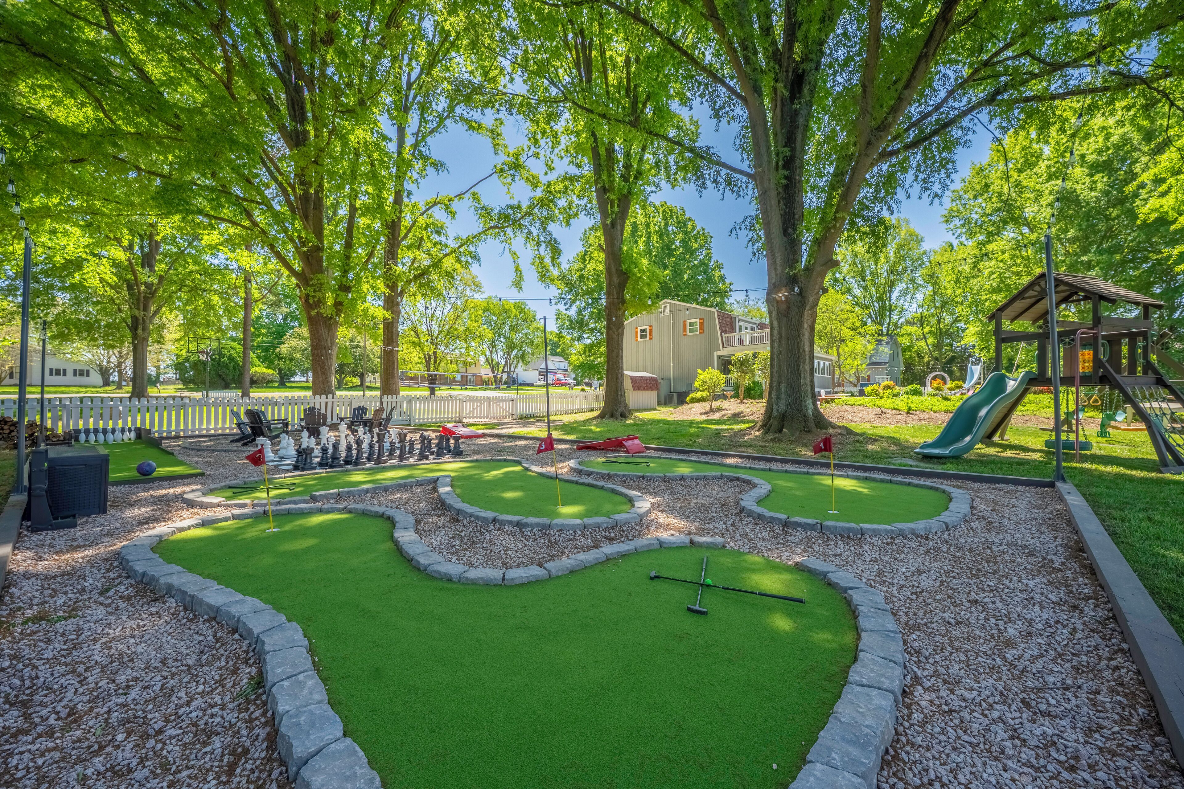 Ein Minigolfplatz mit Putting Green, Sandfalle und einem kleinen Gebäude im Hintergrund.