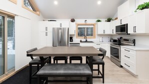 A modern kitchen with white cabinets, stainless steel appliances, and a large window.