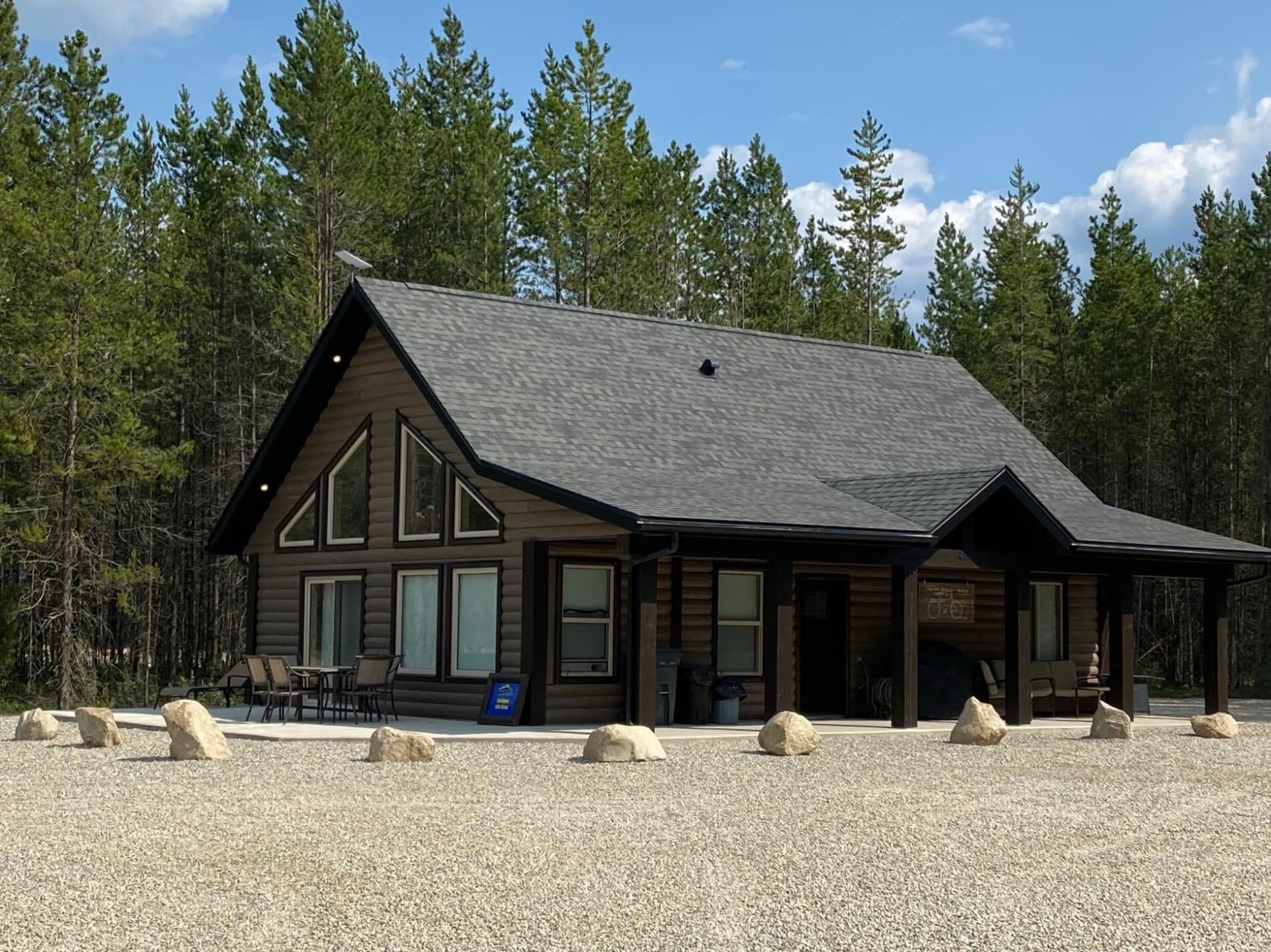 Un chalet doté d’une grande véranda, de nombreuses fenêtres et d’une allée gravillonnée.