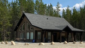 A lodge with a large porch, multiple windows, and a gravel driveway. - The Alpine Cabin Rental (British Columbia)
