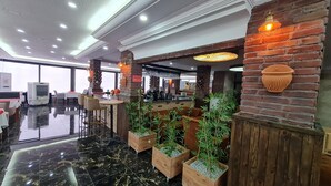 A modern bar area with brick accents, wooden planters with greenery, and a polished marble floor.