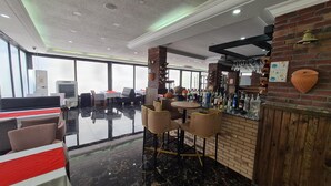 A modern bar area with a brick wall, a polished black marble floor, and a seating area with cushioned chairs and tables.