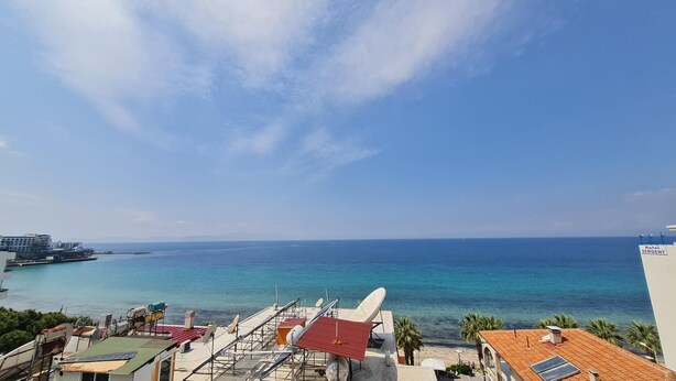 A coastal view with a clear sky, a beach, and a hotel named "Hotel Sergent" in the distance.