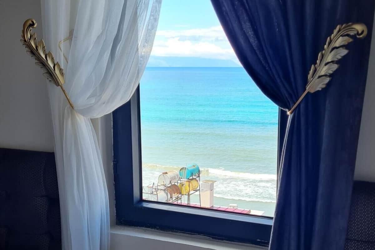 Una habitación con una cama, una mesita de noche con un control remoto y una ventana con cortinas.