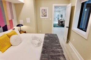 Hotellihuone, jossa on sänky, lamppu, taulu ja näkymä ruokailutilaan.