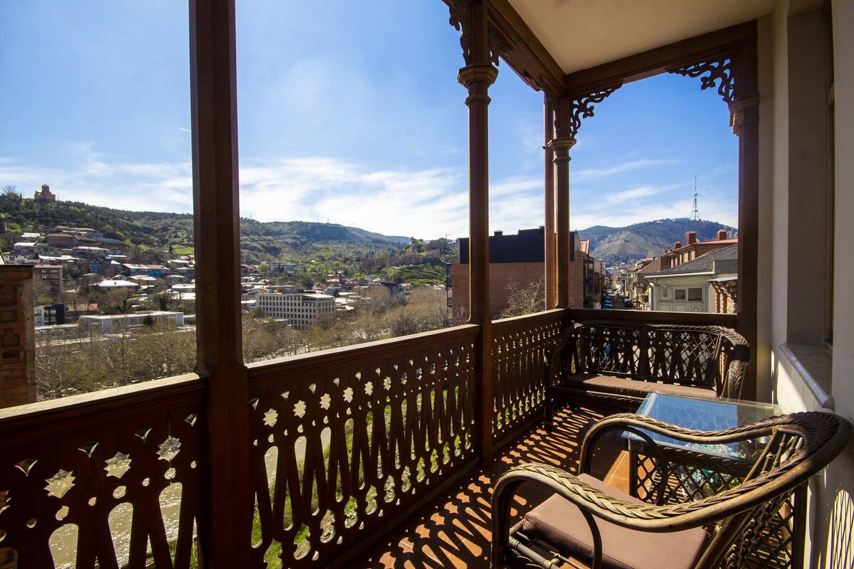 A balcony with a view of a town and hills.