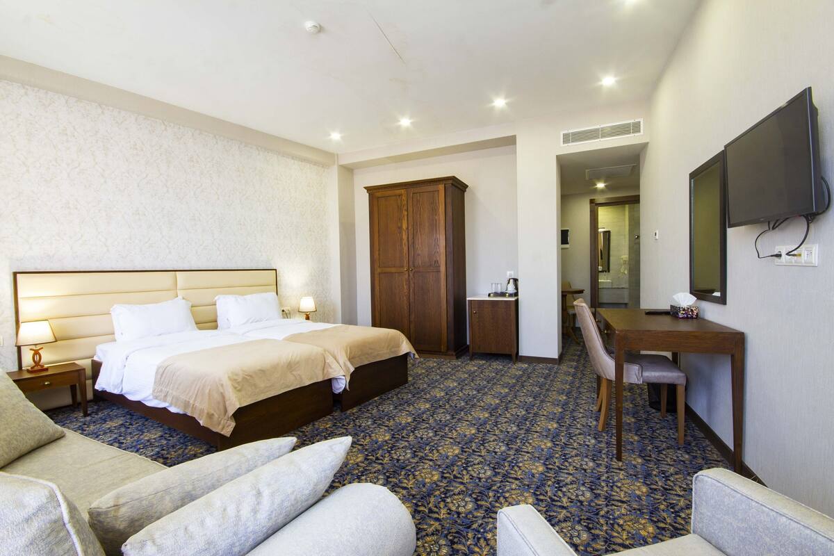 A hotel room with a bed, a desk, a chair, a TV, and a wardrobe.