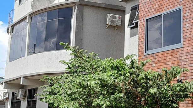 Um edifício com várias andares, varandas, janelas amplas e aparelhos de ar condicionado.