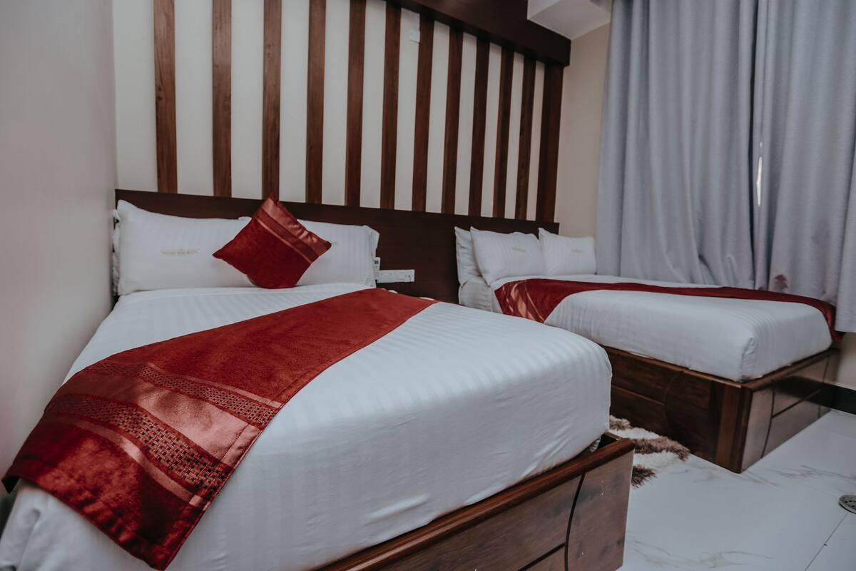 Habitación de hotel con dos camas, cabeceros de madera, ropa de cama blanca y piso de mármol.