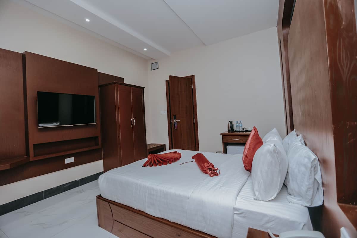 Una habitación de hotel con cama, televisión, muebles de madera y una mesita con hervidor.