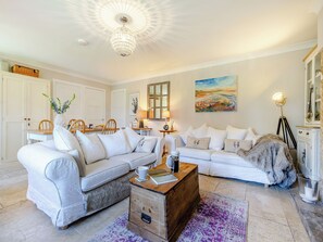 A living room with a white sofa set, a wooden coffee table, and a chandelier.