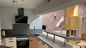 A modern kitchen with a built-in oven, a sink, and a stove. There is a brick wall and a wooden cabinet.