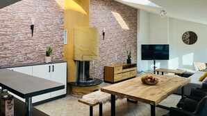 A modern kitchen with a stone wall, a central wooden column, and a built-in fireplace.