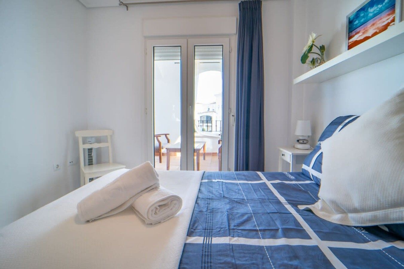 Une chambre d’hôtel avec un lit, une petite table de chevet, une chaise, une fenêtre avec des rideaux et une vue sur l’extérieur.