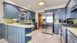 Une cuisine moderne avec des armoires bleues, un réfrigérateur en acier inoxydable et une cuisinière encastrée.