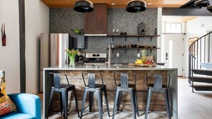 Une cuisine moderne dotée d’un îlot central, de tabourets de bar et d’un escalier menant à un niveau supérieur.