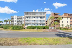 A multi-story hotel with balconies, a parking lot, and a clear blue sky. - Updated 3 BR Oceanfront Condo - Drayton House 402 (Myrtle Beach)