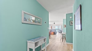 A hallway with teal walls, a white console table, and a rug. - Updated 3 BR Oceanfront Condo - Drayton House 402 (Myrtle Beach)