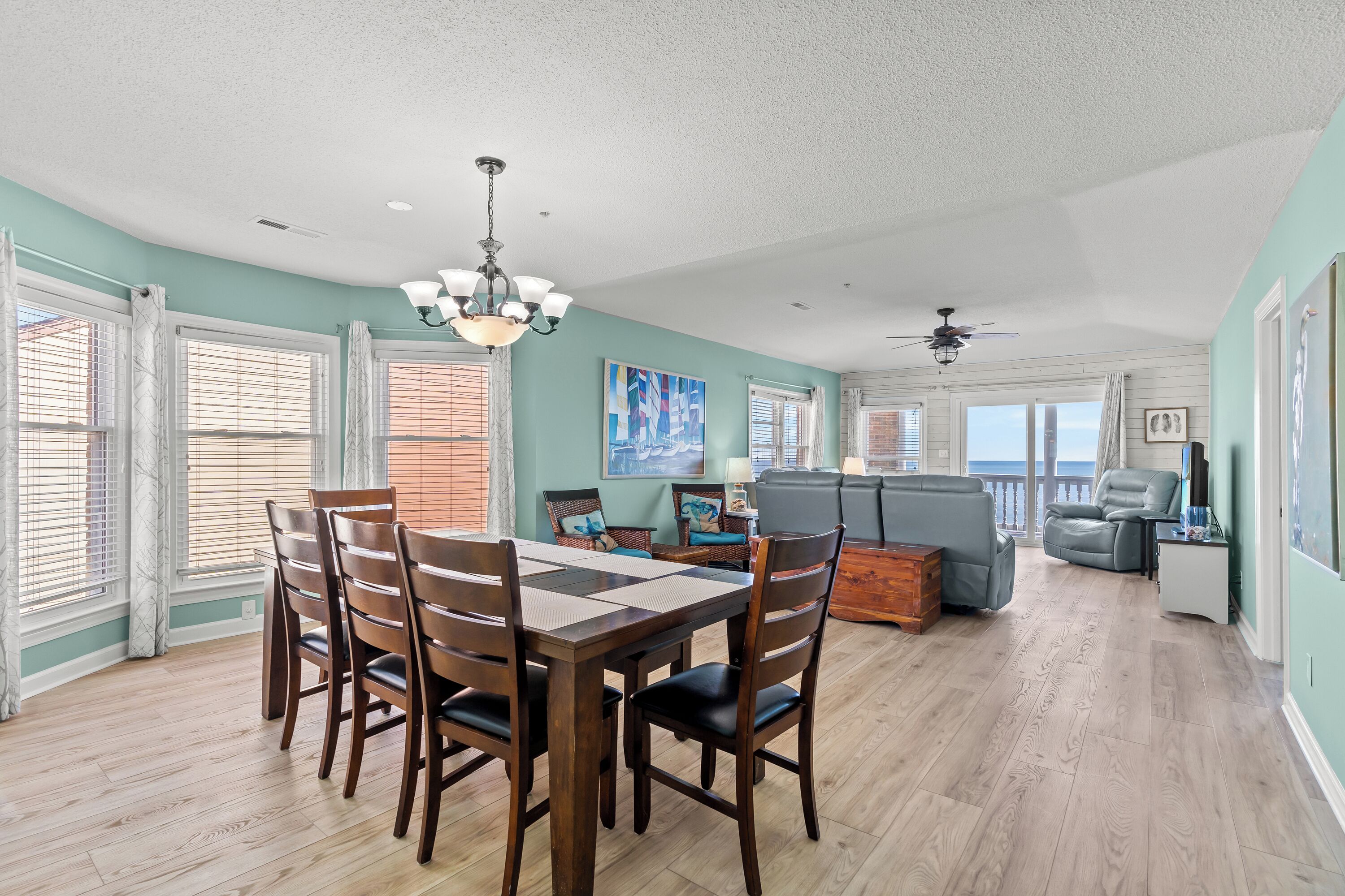 A spacious living area with a dining table, chairs, a sofa, and a ceiling fan.