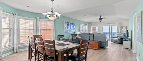 A spacious living area with a dining table, chairs, a sofa, and a ceiling fan.