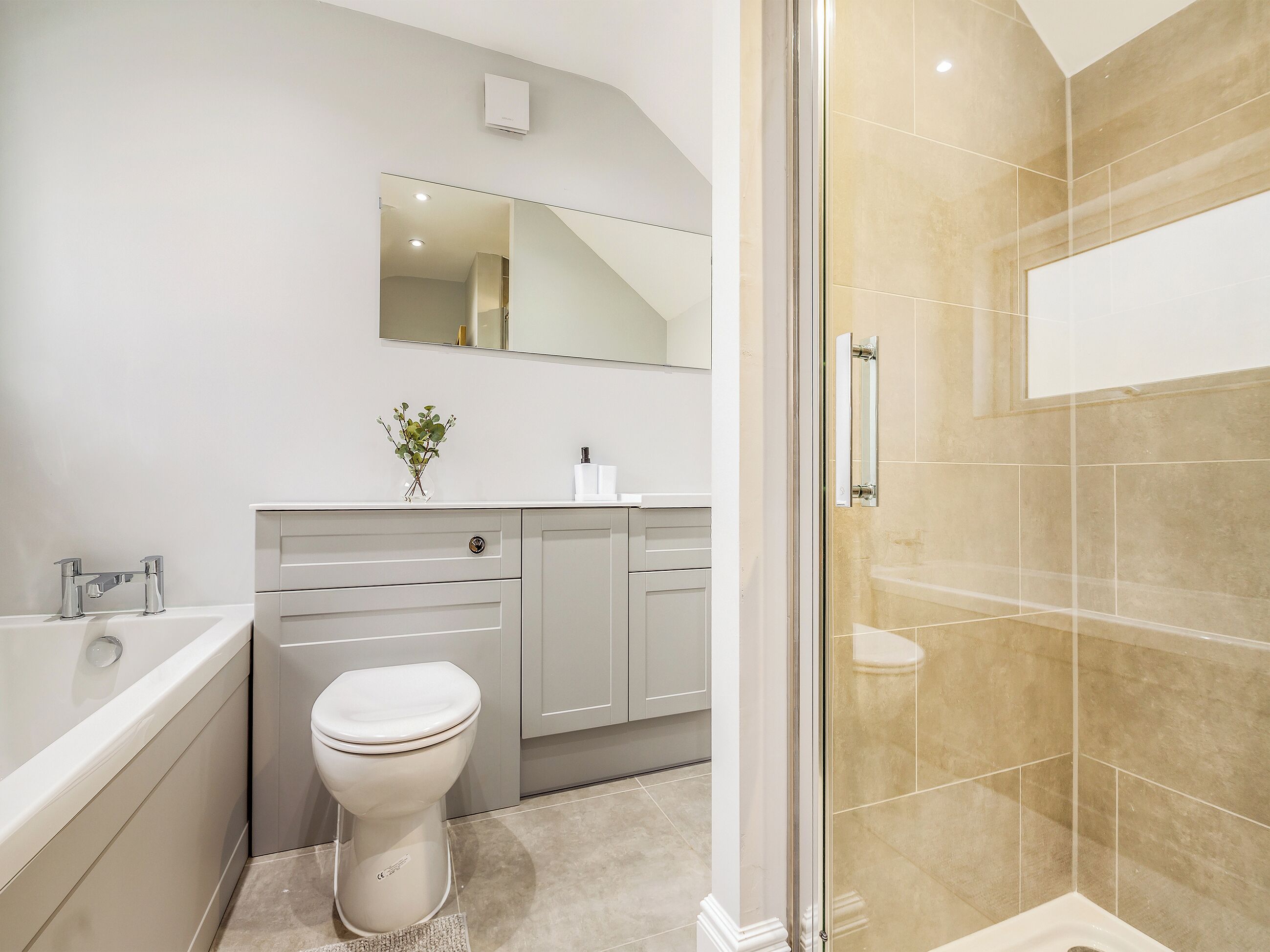 A modern bathroom with a bathtub, toilet, vanity, and a glass-enclosed shower area.