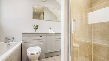 A modern bathroom with a bathtub, toilet, vanity, and a glass-enclosed shower area.