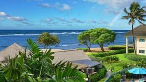 Vista costera con una casa, palmeras y una playa.