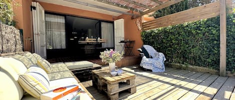 A wooden deck with a sofa, a small table with books, and a covered seating area.