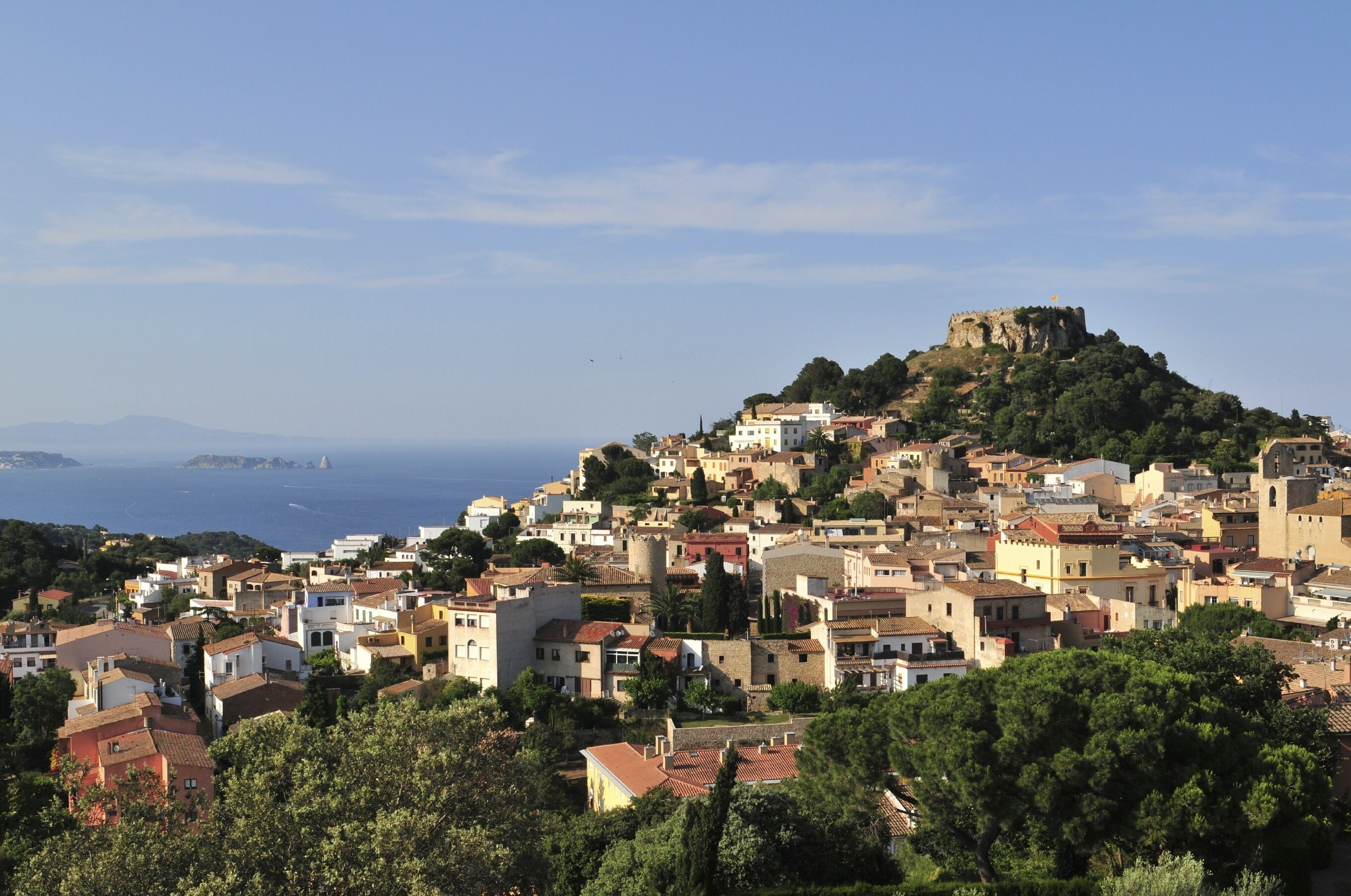A coastal town with historic architecture, a prominent castle on a hill, and a view of the sea.