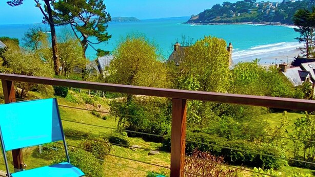 A balcony with a table, chairs, and a glass of drink. - Appart vue Mer, 100m de la Plage, Avec Terrasse et Parking Privé (Perros Guirec)