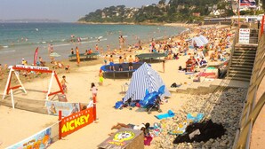 A crowded beach with a volleyball net, a trampoline, and a lifeguard stand. - Appart vue Mer, 100m de la Plage, Avec Terrasse et Parking Privé (Perros Guirec)