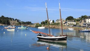 A harbor with boats, calm water, and houses in the background. - Appart vue Mer, 100m de la Plage, Avec Terrasse et Parking Privé (Perros Guirec)