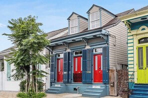 Una fila di case colorate con diversi stili architettonici, tra cui una con una porta rossa e persiane blu.