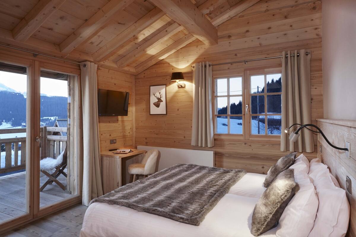 Un dormitorio de cabaña de madera acogedor, con cama, escritorio y silla.