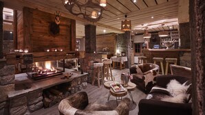 Un interior rústico con chimenea de piedra, vigas de madera y mobiliario de cuero.