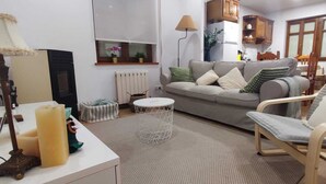 Un salon comprenant un canapé, un fauteuil, une table basse ronde et une lampe.