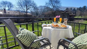 Un balcon avec une table préparée pour le petit-déjeuner, comprenant des croissants, du jus d’orange et une tasse de café.