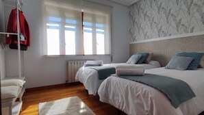 Une chambre avec deux lits, un radiateur, une fenêtre avec des stores et un mur à motifs.